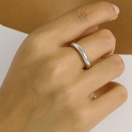 ミニマリストのシルバーのステンレススチールリングを着用したモデル、ツートンのスタッカブルセットから。