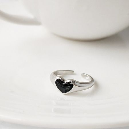 Silver Plated Black Enamel Heart Open Finger Rings - Close-up of a silver-plated ring with a black enamel heart, part of a five-piece set, displayed on a white saucer.