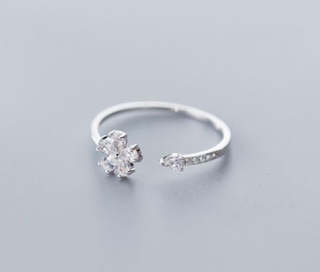 Toma detallada del anillo de flor de plata con su diseño de banda abierta único y acentos de piedras preciosas claras.