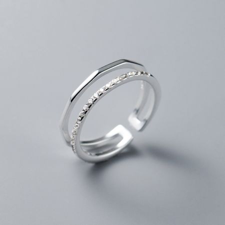 Gedetailleerd uitzicht op een verstelbare ring van sterling zilver met een dubbelbandontwerp en diamantachtige versieringen.