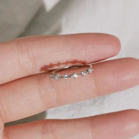 반짝이는 지르콘 링 세트의 은색 버전을 들고 있는 손, 그 빛나는 광채를 보여줍니다.