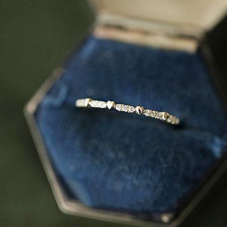 Un gros plan d'une bague en zircon argenté du set, présentée dans une luxueuse boîte en velours bleu.