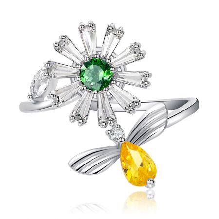 Draaiende bloembijenring - Close-up van de Spinning Flower Bee-ring, met de centrale groene zirkonia-steen in een bloemensetting en een geel zirkonia-bijaccent op een gerhodineerde koperen band.
