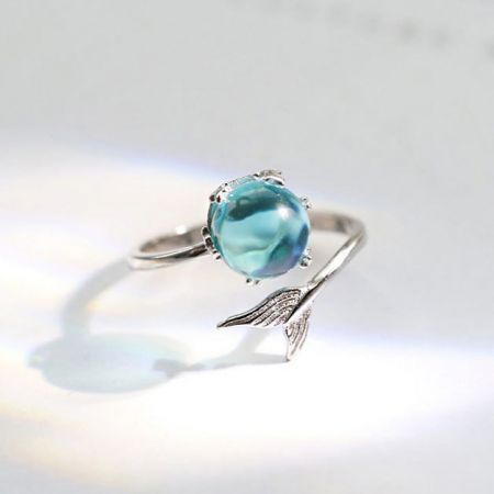 Set di 5 anelli in argento sterling 925 con design ad apertura a forma di coda di sirena per l'indice - Un primo piano di un anello in argento sterling 925 della serie a motivo coda di sirena, con un design intricato a forma di ala e una pietra azzurra chiara scintillante.
