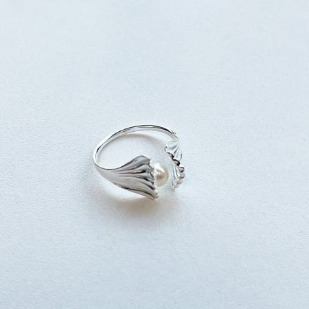 Vista detallada de un anillo de plata esterlina del conjunto, con una perla central y delicados acentos de hojas.