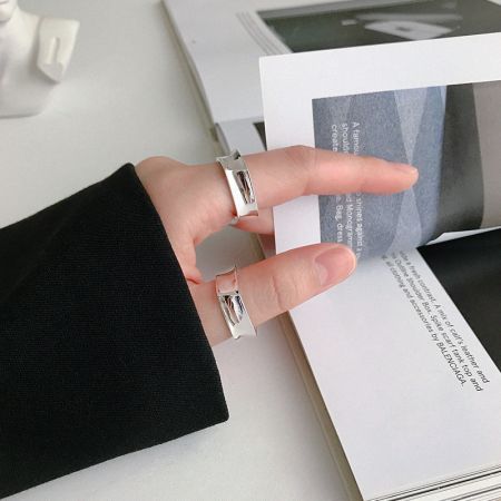 幾何学的な925スターリングシルバーのリングを2つ着けた手で、日常の女性ファッションにぴったりなミニマリストスタイルを紹介しています。