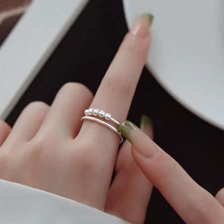 Anello d'ansia con perline rotanti in argento sterling regolabile (set di 5) - La mano di una donna che indossa due anelli d'ansia in argento sterling con perline rotanti regolabili, mostrando il loro design elegante e la vestibilità.