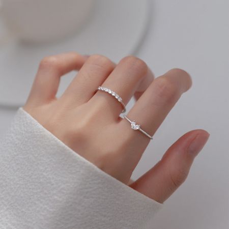 Ensemble de bagues en argent 925 en forme de papillon et de cœur en CZ, cadeau d'amitié personnalisé - Gros plan d'une main portant deux élégantes bagues en argent sterling 925, l'une avec une pierre CZ en forme de cœur scintillante et l'autre une délicate bande en forme de papillon.