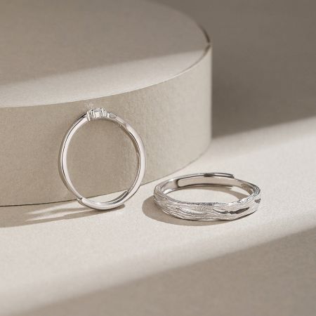 Ensemble de bagues de couple ajustables en argent sterling 925 avec design de branche. - Une paire de bagues de couple en argent sterling 925 avec un design de branche ajustable, l'une ayant un bandeau lisse et l'autre un motif de feuille texturé.