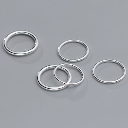 Anelli impilabili semplici in argento sterling 925 (Set di 5) - Un set di cinque anelli impilabili in argento sterling 925 con un design elegante e moderno, mostrati su uno sfondo neutro.
