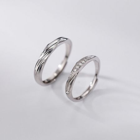 Ensemble assorti de bagues pour couples en argent sterling 925 - Ensemble de bagues pour couples en argent sterling 925, élégant, comprenant une bande polie et une bande avec des pierres en zircon cubique, sur fond blanc.