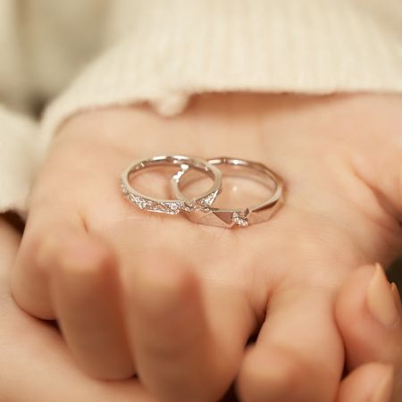 Ein weiteres Lifestyle-Foto, das die Eheringe aus Sterlingsilber für ihn und sie an einer Hand zeigt.