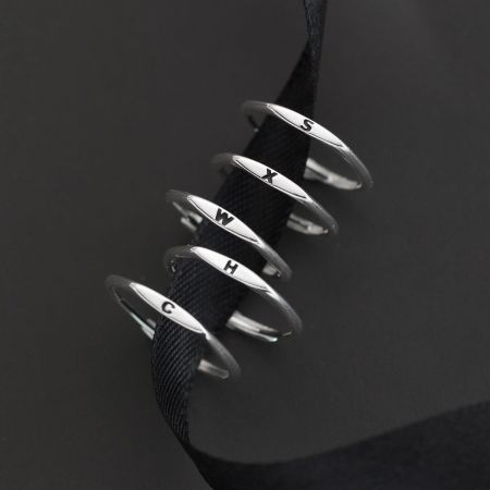 Close-up of five sterling silver alphabet rings with letters C, H, W, X, and S.