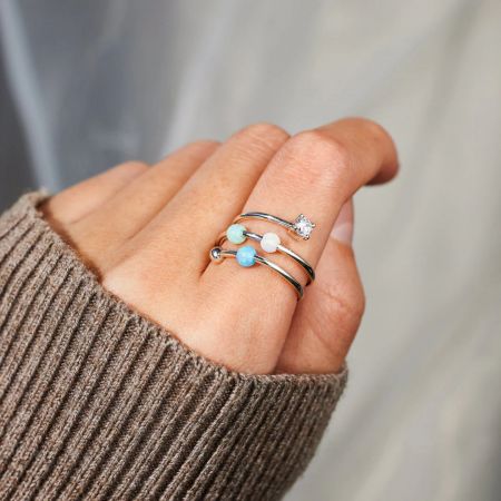 Ein Modell trägt die Starlit Ocean Ringe aus 925er Sterlingsilber mit Opal und Zirkon an ihrem Finger.