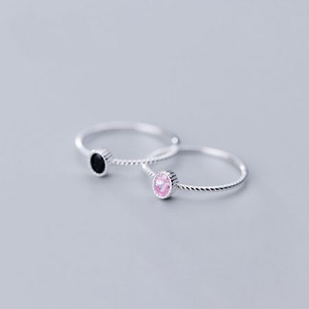 Ovanifrån vy av sterling silverringar med rosa och svarta kubiska zirkonior.