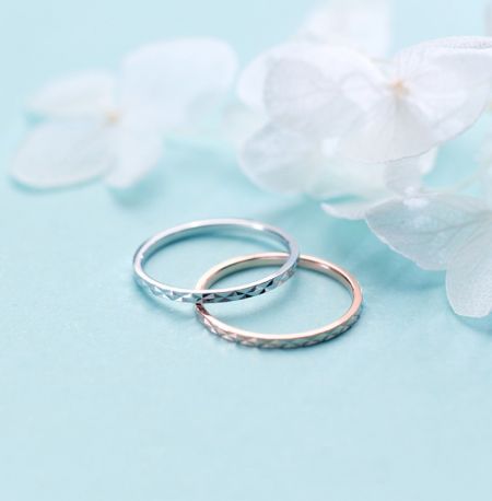 Gros plan de deux bagues en argent sterling avec taille de diamant et un extérieur texturé sur une surface bleue.
