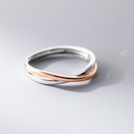 Die Herrenvariante des Möbius-Rings, mit einem markanten Design aus verflochtenen Silber- und Roségoldbändern.