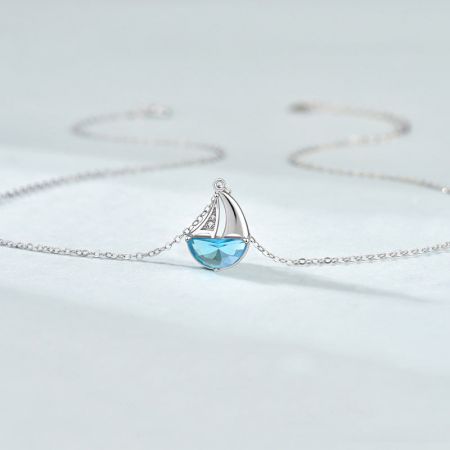 Detailed view of the sailboat pendant with its intricate light blue CZ gemstone.