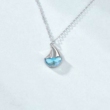 Collar con colgante de velero CZ de plata esterlina 925. - Primer plano de un collar con colgante de velero de plata esterlina 925, con un casco de piedra preciosa CZ azul claro y piedras CZ blancas brillantes en la vela.