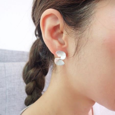 Modello che indossa gli eleganti orecchini a perno a forma di ventaglio a arco S in argento.