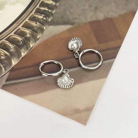 Primo piano della variante in argento dell'orecchino a cerchio huggie con perla oceanica, che mostra dettagli intricati della conchiglia.
