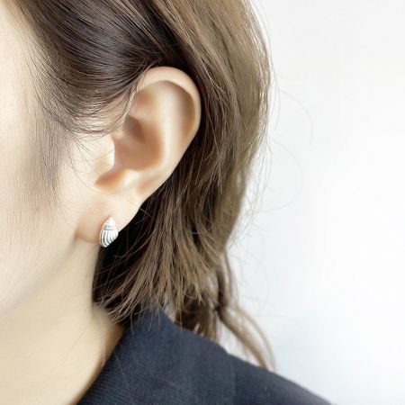 Modello che indossa l'orecchino a perno a forma di conchiglia in argento sterling per mostrare scala e stile.