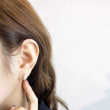 Vista ravvicinata dell'orecchino a forma di conchiglia in argento sull'orecchio di un modello, enfatizzando il suo design elegante.