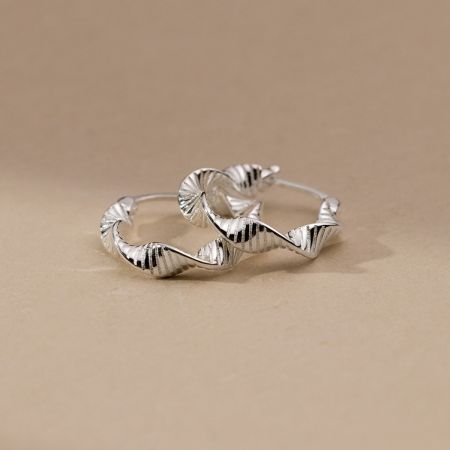 Un paio di orecchini a cerchio in argento sterling con una texture unica ondulata, simile a una conchiglia.