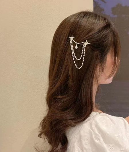 Modelo usando el clip para el cabello con estrella plateada colgante, mostrando su aspecto elegante en cabello largo castaño.