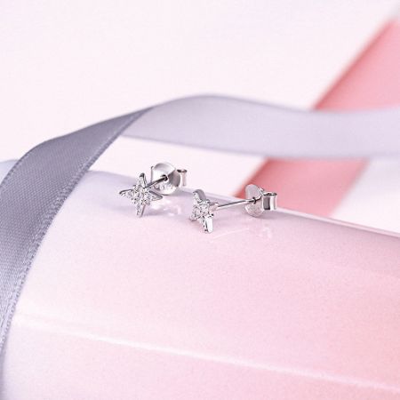Un paio di orecchini a stella ottagonale in argento con gemme trasparenti su un supporto espositivo.