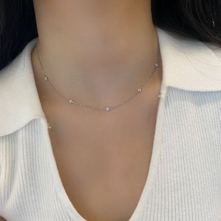 Collar de trébol de cuatro hojas de plata de ley 925 con baño de oro de 18K y circonitas cúbicas. - Una modelo que lleva un elegante collar de plata de ley 925 con temática de estrellas, con baño de oro de 18K y circonitas cúbicas, parte de un conjunto de cinco piezas.