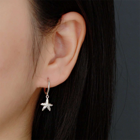 Un modello che indossa gli orecchini huggie a forma di stella marina in argento sterling 925 per mostrare la loro dimensione e stile.