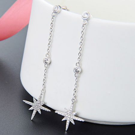 Primo piano degli orecchini a forma di stella in argento sterling 925 con pietre trasparenti scintillanti.