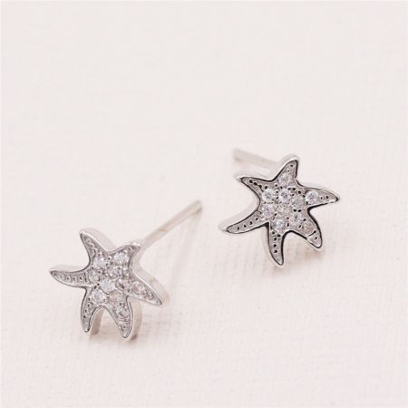 Orecchini in argento sterling 925 con piccole stelle marine irregolari sull'oceano (5 paia) - Un paio di orecchini a forma di stella marina in argento sterling 925, dettagliati in modo intricato con piccole gemme trasparenti, presentati su uno sfondo bianco pulito.