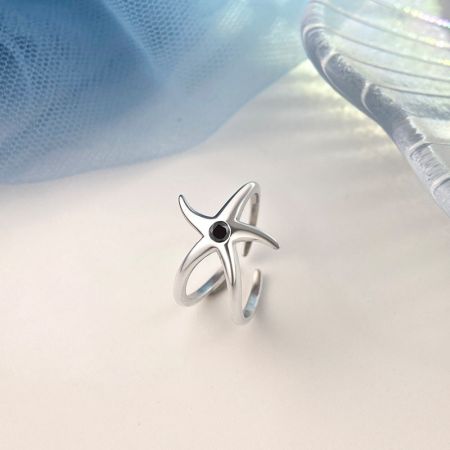 Primer plano del anillo de estrella de mar de plata S925 con una gema negra.