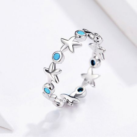 Set di 5 anelli a fascia in argento sterling 925 con zirconia blu oceano a forma di stella marina - Un set di cinque anelli in argento sterling 925 con un design a forma di stella marina ispirato all'oceano, adornati con scintillanti pietre di zirconia blu oceano, esposti su uno sfondo neutro.