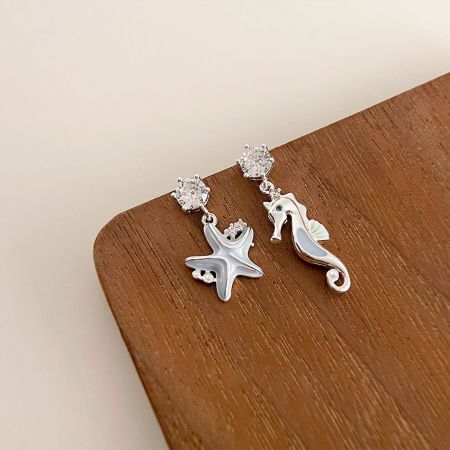 Light Blue Enamel Starfish and Seahorse Asymmetrical Drop Earrings - A pair of asymmetrical ocean-themed drop earrings featuring a silver starfish and a seahorse, both accented with clear gemstones, on a clean white background.