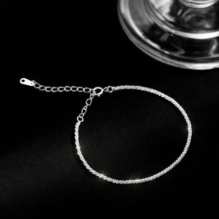 Un brazalete de plata de ley con intrincadas incrustaciones de piedras.
