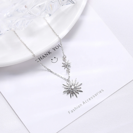 A clear product image of the silver sun-themed necklace against a neutral backdrop.
