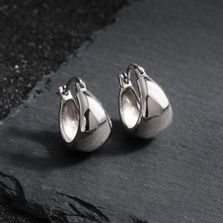 Pendientes de aro gruesos de tubo de plata esterlina 925 al por mayor, bañados en oro blanco para el uso diario de mujeres. - Un par de pendientes de aro gruesos de plata esterlina 925 al por mayor con un acabado bañado en oro blanco, mostrando su forma minimalista similar a una gota y su cierre seguro.