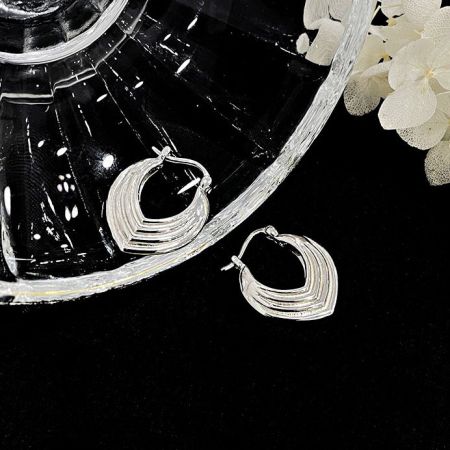 Gli orecchini in argento sterling esposti su una superficie scura per enfatizzare la loro lucentezza metallica.