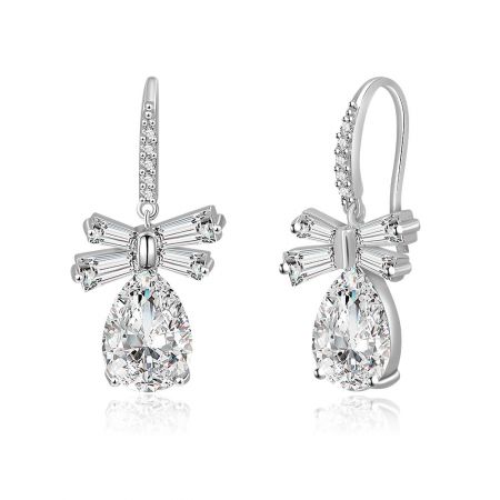 Gedetailleerde close-up van de Witte CZ Ovale Dangle Strik Oorbellen, met de ingewikkelde strik bovenkant en de kwaliteit van het zilverkleurige metaal.