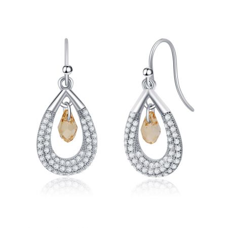 Primo piano degli orecchini a goccia di cristallo Swarovski, evidenziando il brillante scintillio delle gemme chiare e giallo pallido contro l'argento lucido.