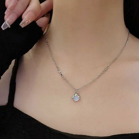 A model wearing a brass necklace with a teardrop resin stone.