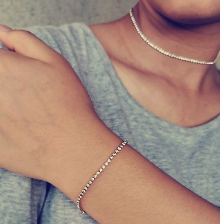 Modèle portant l'élégant ensemble de collier et bracelet en acier inoxydable de ton argent.