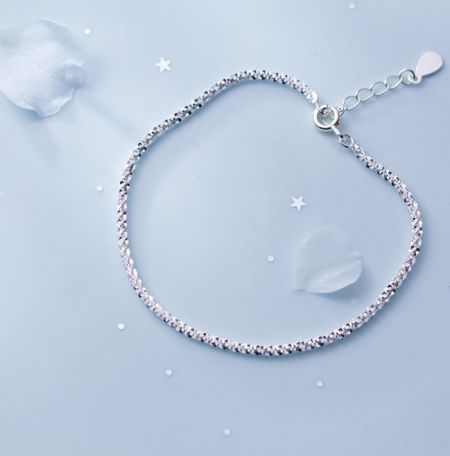 Gedetailleerd uitzicht op de textuur van de 925 Sterling Zilveren Glanzende Armband op een blauwe ondergrond.