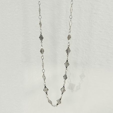 Close-up of the silver waist chain with a unique textured finish on its diamond-shaped elements.