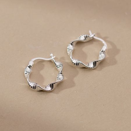 Vista dettagliata della texture ondulata sugli orecchini a cerchio geometrici in argento sterling 925.
