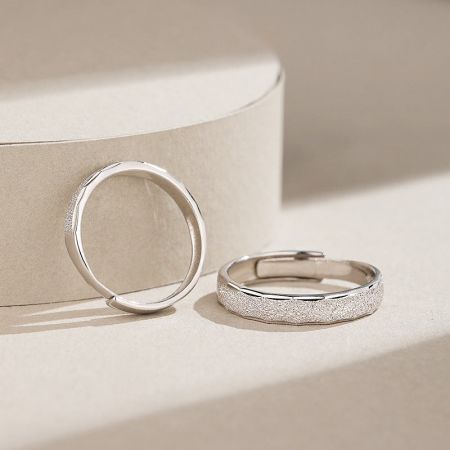 Close-up view of the couple promise rings, highlighting the textured exterior and smooth interior.