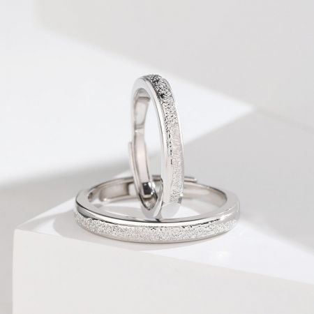 Una vista dettagliata delle fedi nuziali in argento sterling, che evidenzia la loro superficie testurizzata e il design della banda regolabile.